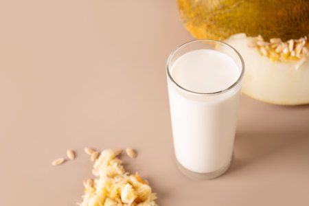 Raw Melon Seeds Milk and seeds on beige background. Close up. Alternative vegan fruit based milk.