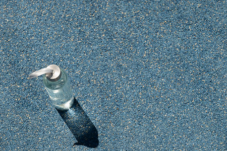 Transparent refreshing glass bottle of water in sunny day with hard shadow on outdoor sports ground. Concept water balance for heat season for workout. View from above. Copy space.の写真素材