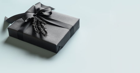 Black gift box with bow on blue background. Banner. Close up. Copy space. Present for Father Day,...