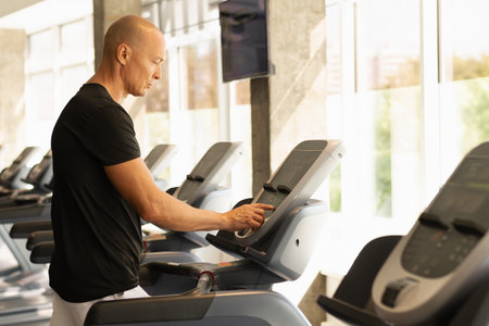 Athlete man walking on running track, warming up on gym treadmill. Running at the gym. Close up.