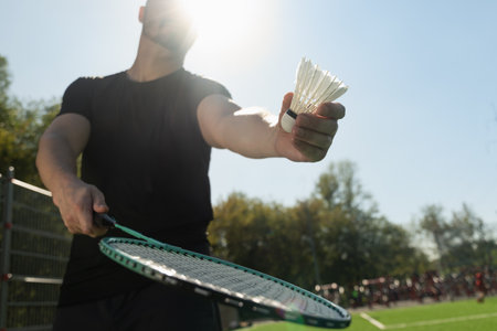 Man playing badminton on floor sport court in sunny shadow. Outdoors. Close up.の写真素材