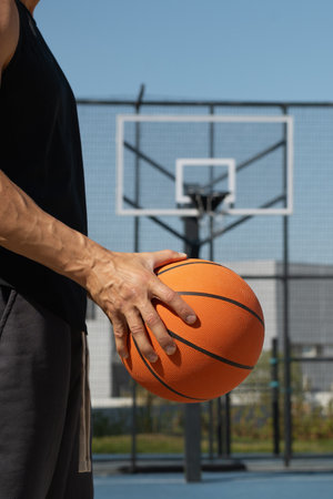 Basketball orange ball in mans hand on sport court. Sport background. Team sport. Vertical format.の写真素材