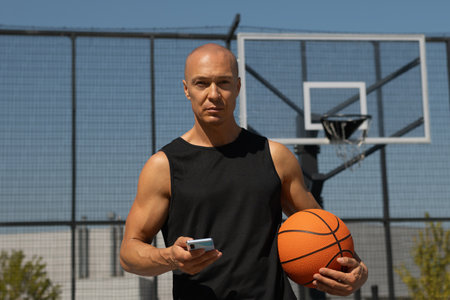 Sports caucasian man or basketball player using smartphone after outdoor training and looking at camera.の写真素材