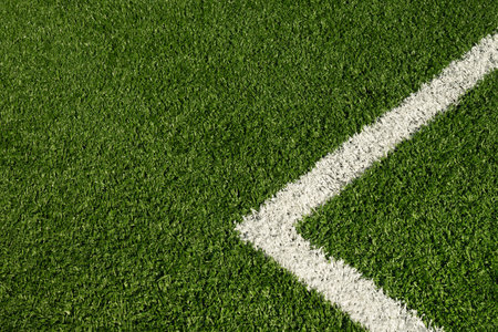 Artificial green grass with white stripe of soccer field. Outdoors. Summer. View from above.