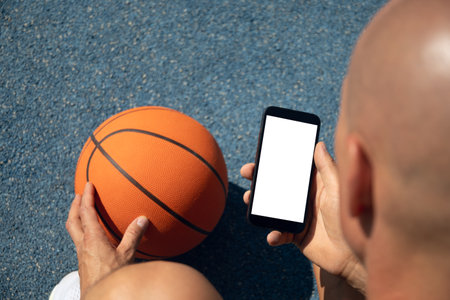 Basketball player using smartphone and social media during game interval. Sports mock up. View from above.の写真素材