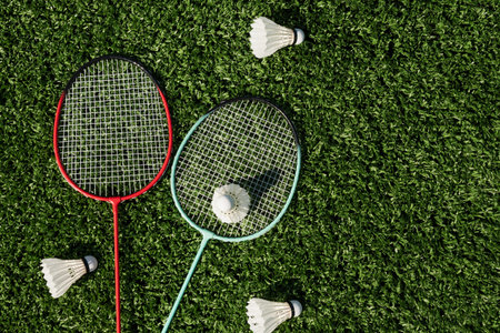 Badminton rackets and white badminton shuttlecocks on green lawn. Summer leisure games. Outdoors. View from above.の写真素材
