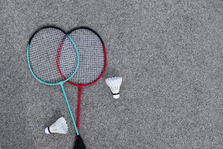 White badminton shuttlecock and badminton rackets for two on floor sport badminton court. Outdoors. Leisure games. View from above.の写真素材