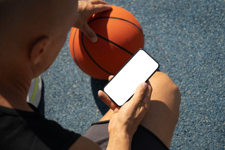 Basketball player using smartphone and texting social media during game interval, Outdoor training. View from above. Close up.の写真素材