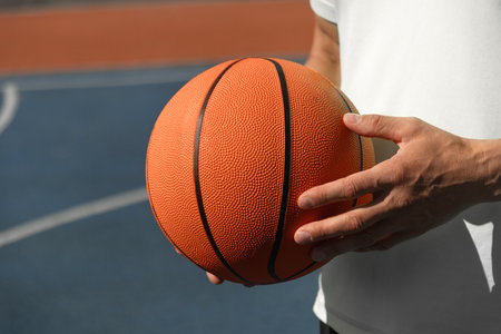 Basketball player, man holding orange ball on sports court. Sports goals competition game, champion outdoor workout. Close up. Copy spaceの写真素材