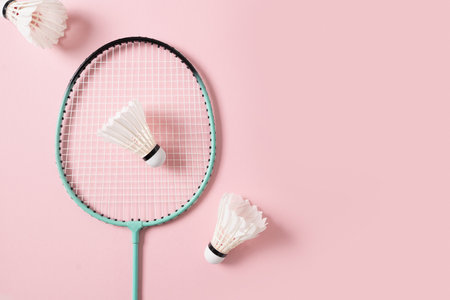 White feather badminton shuttlecocks and badminton racket on light pink background. View from above. Concept racket sport. Leisure games.の写真素材