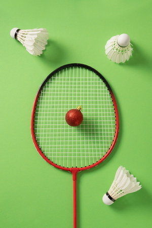 Christmas badminton concept with racket, red ball and white feather badminton shuttlecocks on green background. View from above. Xmas greeting card.の写真素材