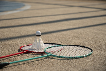 White badminton shuttlecock and badminton rackets on floor sport badminton court in sunny shadow....