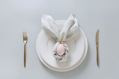 Easter spring table setting with pink egg on gray background. Happy creative Easter decoration. View...