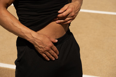 Man holds his abdomen in pain, highlighting discomfort or potential injury during exercise.