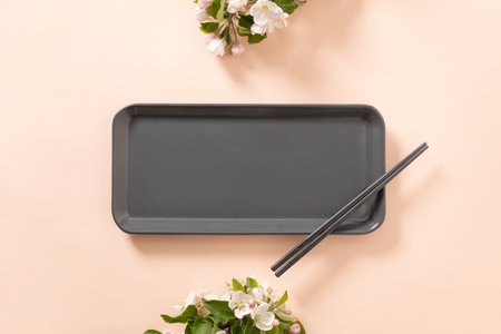 Empty rectangular gray plate for asian food with black chopsticks on pink background surface with...