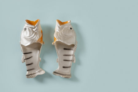 Rubber slippers shaped of fish. Fishermen slippers for beach on blue background. Summer vacation. Creative funny flip flops. View from above. Copy space.の写真素材