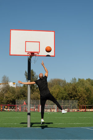 Basketball player or sporty man tries to throw ball into basketball hoop on sports court at...