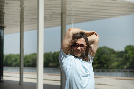 Fit handsome caucasian brunette man wearing sports casual clothes and sunglasses doing warm up...