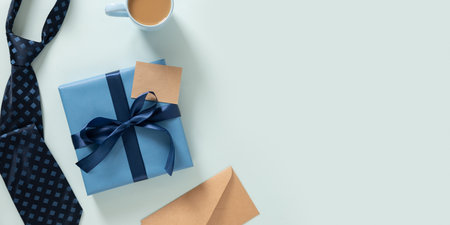 Banner for Fathers Day with gift box, label on blue background. Creative frame classic with dad coffee cup, tie. Mens accessories set. Top view. Copy space.の写真素材