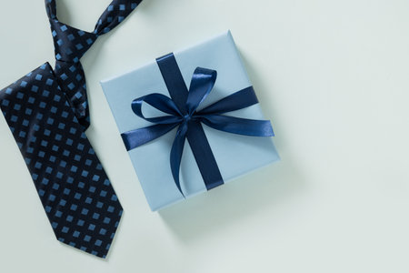 Happy Fathers Day gift box and tie on pastel blue background. Creative concept with mens accessories. Flat lay. View from above. Copy space.の写真素材