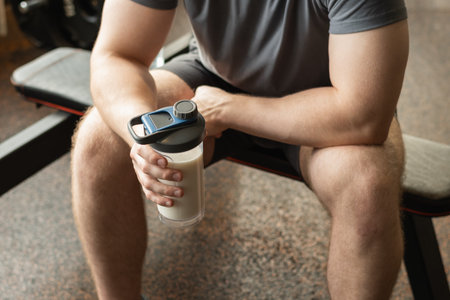Close up shot of man at gym holding protein shaker. Bodybuilder during strength training. Fitness healthy lifestyle concept. Hydration after workout session. Supplement productの写真素材