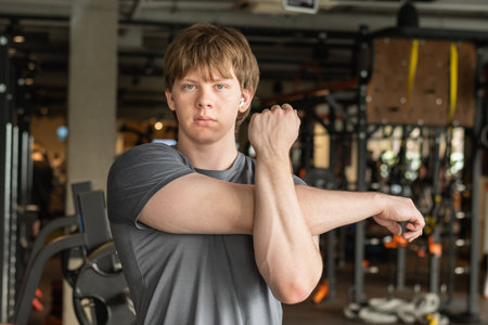Athletic man or fitness trainer stretching with arm before workout, exercise or training at indoor...