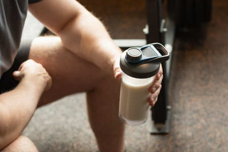 Close up shot of man at gym holding protein shaker. Bodybuilder during strength training. Fitness healthy lifestyle concept. Supplement product, creatine, glutamine for workout.の写真素材