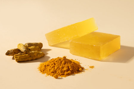 Handmade turmeric soap bars, powder and turmeric root on yellow background. Organic skincare product perfect for wellness, beauty, and organic body care concepts. Vertical. Close up.の写真素材