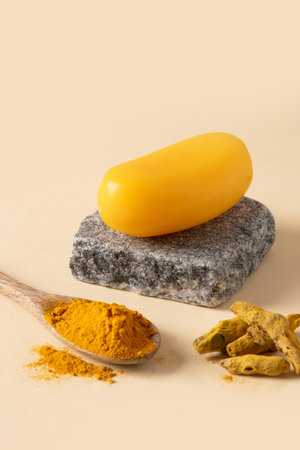 Handmade turmeric soap bar on stone on beige background. Organic skincare product perfect for wellness, beauty, and organic body care concepts. Vertical. Close up.の写真素材