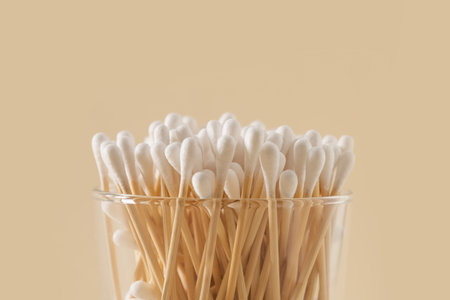 Wooden ecological cotton swab in glass jar on beige background. Zero waste, sustainable resources. Close up.の写真素材
