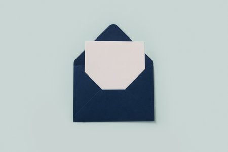 Blue elegant paper envelope and white sheet blank for letter d on blue background. Greeting card. Copy space. View from above.の写真素材