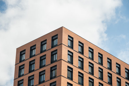 New building of bricks with apartments and modern design. Skyscraper against blue cloudy sky.