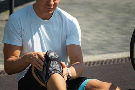 Cyclist injured his knee. Unhappy cyclist with knee pain and injury outdoors. Close up.の写真素材