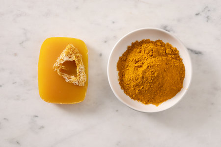 Turmeric soap bar and powder turmeric root on marble white background. Organic skincare product perfect for wellness, beauty, and organic body care concepts. View from above.の写真素材