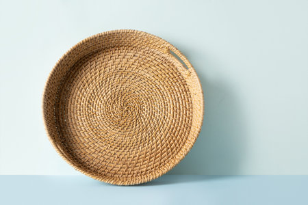 Round woven wicker basket, tray or plate stand on blue background. Handmade by local craftsmen in sri lanka traditional tableware.の写真素材