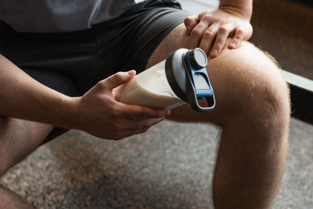 Close up shot of man at gym holding protein shaker. Bodybuilder during strength training. Fitness healthy lifestyle concept. Hydration after workout session. Supplement productの写真素材