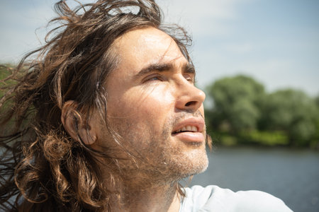 Happy brunette man enjoying and looking to the sun at urban park. Enjoying nature and sunny day. Summer. Breathe in clean airの写真素材