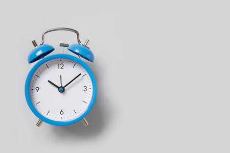 Blue alarm clock on gray background. Space for design. View from above.