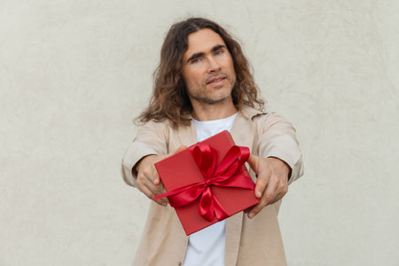 Happy handsome caucasian man giving red gift box with love. Birthday. Romantic surprise and celebration. Greeting card.の写真素材