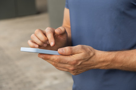 Man using and texting mobile phone. Check apps, focused on device, chatting or browsing internet. Online. Outdoors.の写真素材