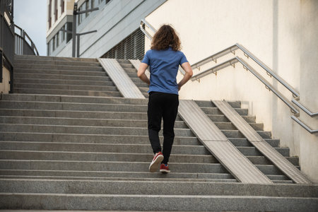 Sporty man and athlete wearing blue t-shirt running at stair in modern city. Cardio workout...
