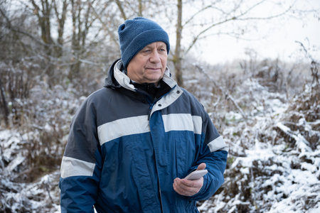 Adult man walks in winter park with unplugged mobile phone. Winter walk in frosty forest. Healthy...