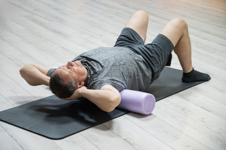 Adult caucasian man doing foam roller exercise for back pain relief. Healthy lifestyle,...