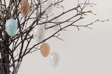 Easter tree decorated white and beige eggs in vase on white . Close up.