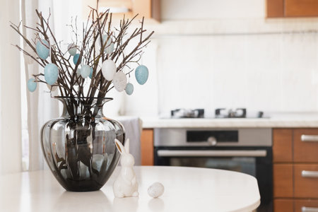 Easter decoration with branches and eggs in vase on kitchen table
