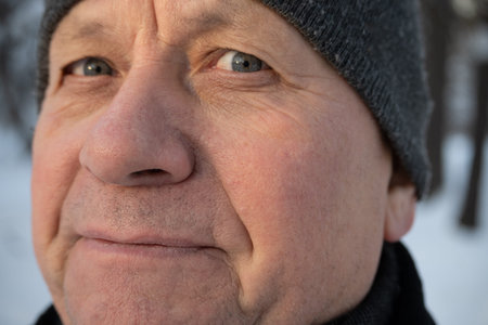 Close up portrait of mature man wearing winter hat outdoors. Natural aging, character and winter...