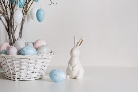 Easter tree with pastel eggs in vase and white bunny figurine vertical