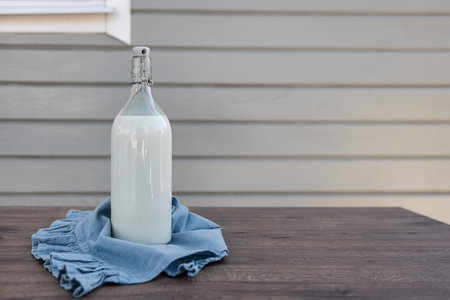 Glass bottle with fresh milk on wooden table with copy space for healthy nutrition farm product and organic food concept
