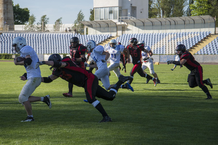 Teams for American football against the backdrop of a green field. Playing American football at the stadium. Match on American football. Men play the ball in a sports stadium.のeditorial素材