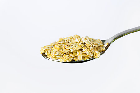 Dry oatmeal with dried fruits in spoons on white backgroundの写真素材